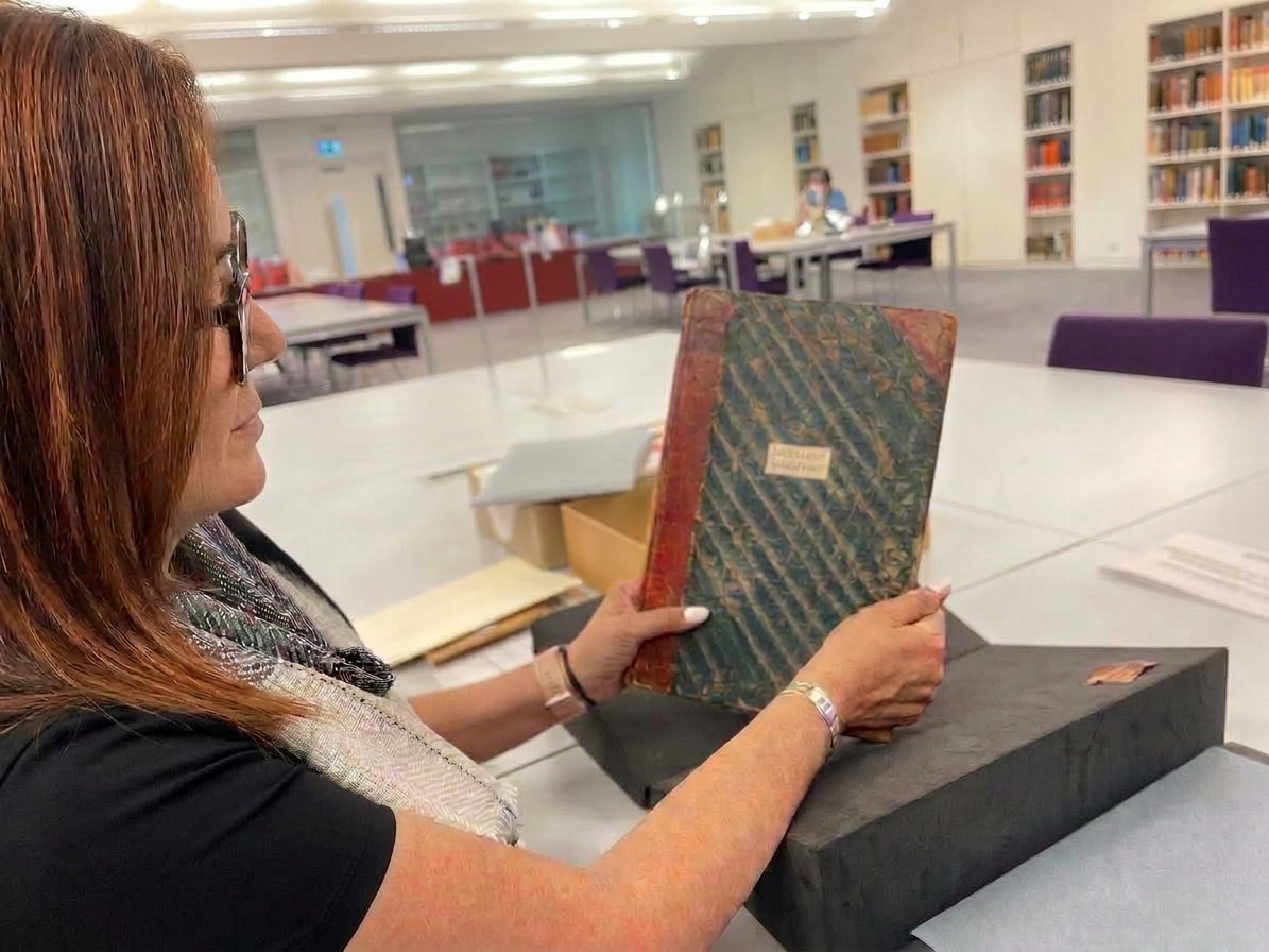 Tobi Iverson holding a bound volume of Arthur Wellington Clah's journals in the reading room at the Wellcome Collection, London